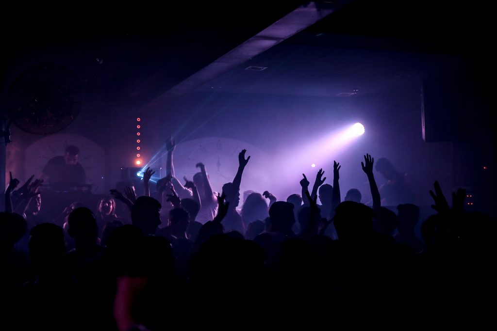 Crowded electronic music club dance floor with spotlights