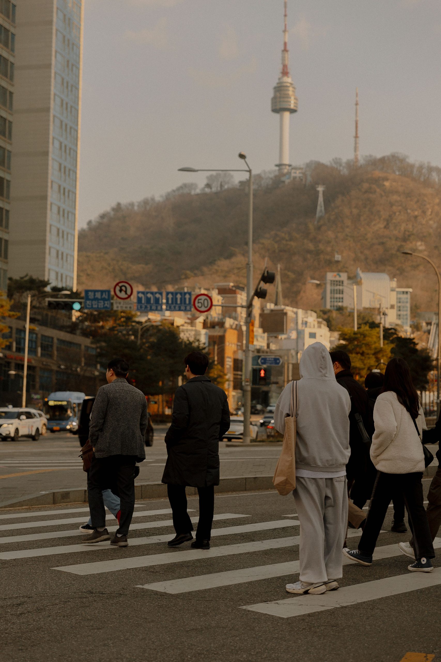 People crossing a street in Seoul with N Seoul Tower in the background